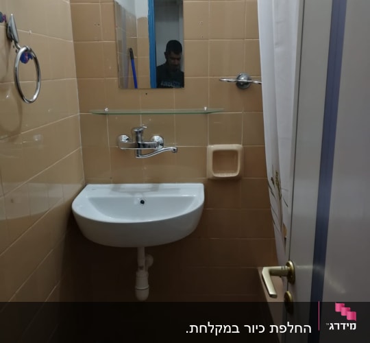 כיור עם ברז ומראה בחדר אמבטיה קטן
